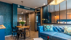 Una sala moderna con un sofá azul, una mesa de comedor de madera y sillas.