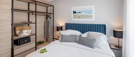 A modern bedroom with a bed, a wooden shelving unit, a wall-mounted picture, and bedside lamps.