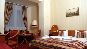 A hotel room with a bed, a desk, a chair, a table, and a lamp. - Schwarzer Bär (Zittau)