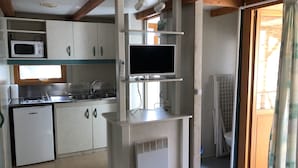Een keukentje met een magnetron, spoelbak en een kleine koelkast.