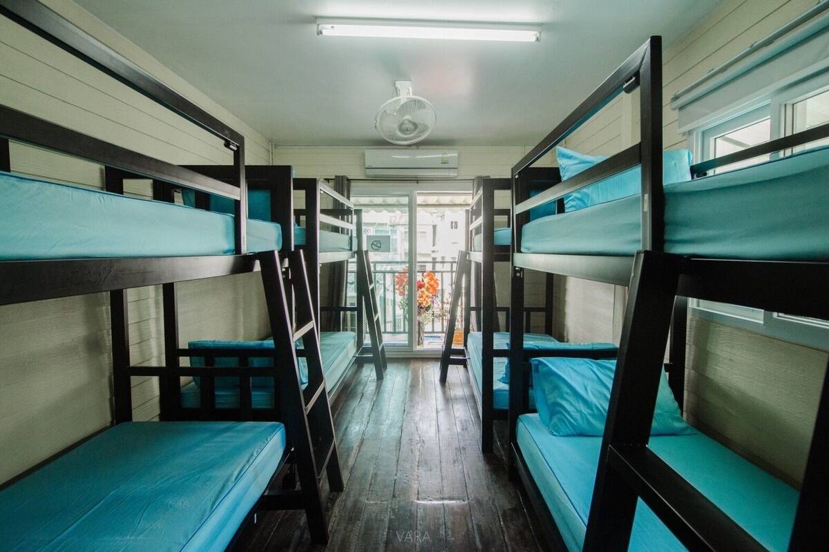 Een slaapkamer met stapelbedden van hout en een plafondventilator.