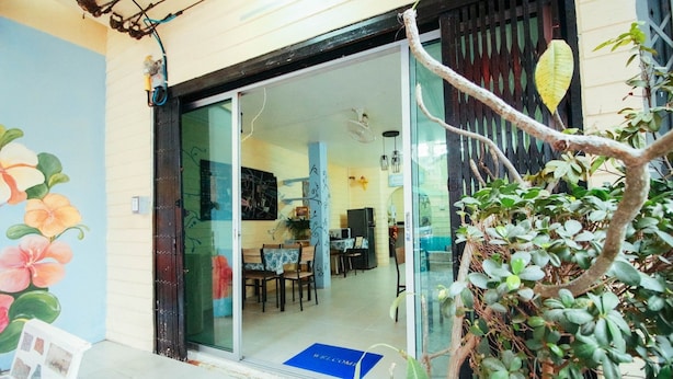 Un restaurant avec une entrée dotée d’une porte en verre, des tables à l’intérieur et un paillasson bleu devant la porte.