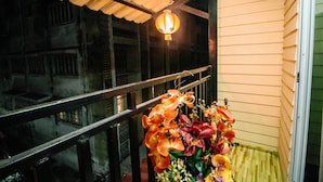 Un balcon avec une balustrade, une jardinière suspendue et une lanterne.
