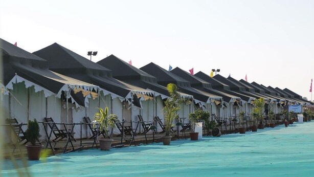 A row of beachside huts with a turquoise pool in front. - TSI Kumbh Mela Camp (Prayagraj)