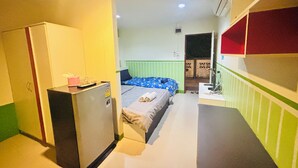 A compact hotel room with a bed, a small desk, a wardrobe, and a kitchenette. - Sabaidee Place (Phetchabun)