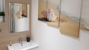 A bathroom with a white sink, a mirror, and three framed pictures of seashells on the wall. - First St John's Hill Apartment 2 (Edinburgh)