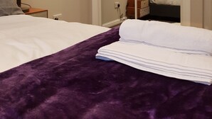 A hotel room with a bed, a nightstand, a lamp, a purple throw blanket, and a mirror reflecting a bed with pillows. - First St John's Hill Apartment 2 (Edinburgh)