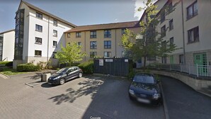 A residential building with a gated parking area, a car, and a pedestrian pathway. - First St John's Hill Apartment 2 (Edinburgh)
