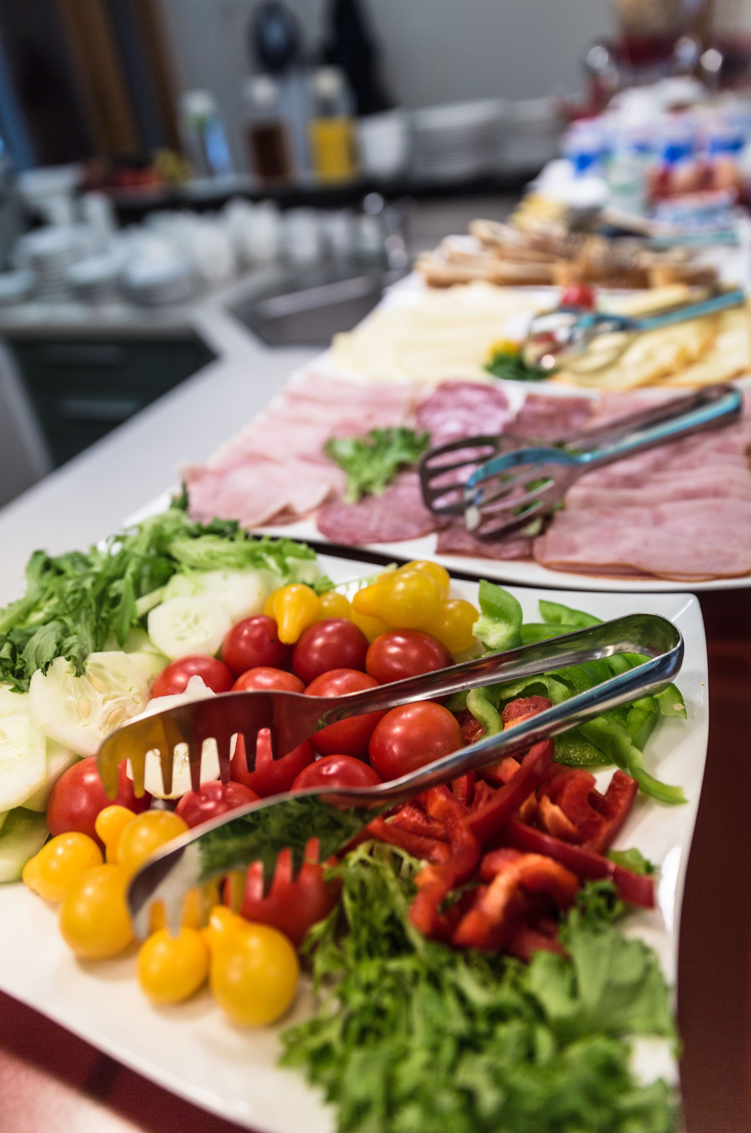 Een buffet met diverse etenswaren, waaronder groenten, vlees en kazen.