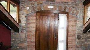 Une porte en bois dans une pièce aux murs de pierre, dotée d’un plafond en pente et de poutres en bois.