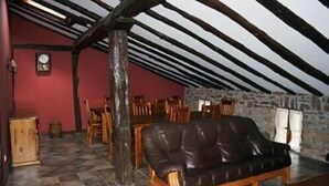 Une pièce mansardée chaleureuse, avec un canapé en cuir, des chaises en bois, une table à manger et un mur en pierre.
