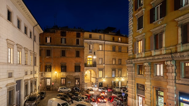 A narrow street with parked cars and buildings on both sides. - Tula Inn (Rome)