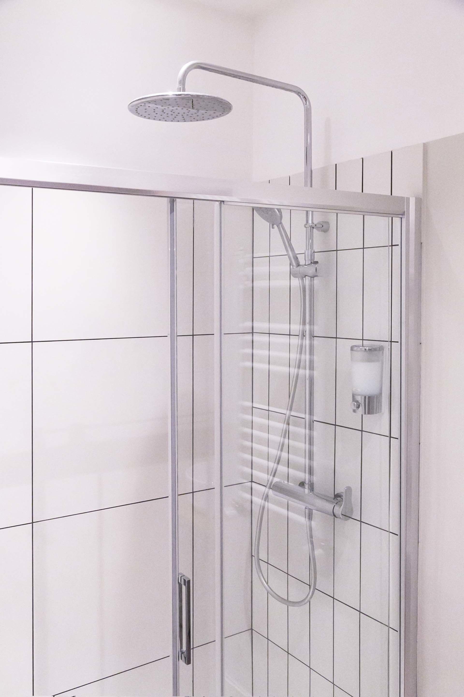 A walk-in shower with a handheld showerhead, a handheld shower attachment, and a handheld shower hose.