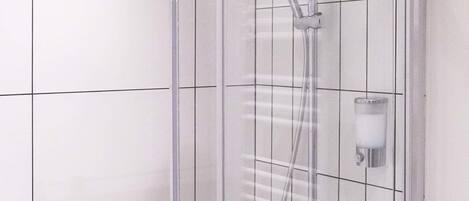 A walk-in shower with a handheld showerhead, a handheld shower attachment, and a handheld shower hose.