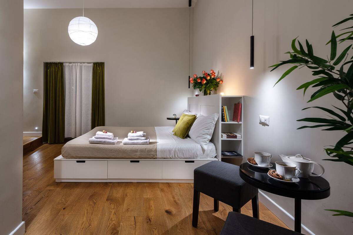 A modern bedroom with a bed, bedside table, and a small seating area.