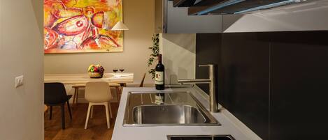 A modern kitchen with a stainless steel sink, a built-in stove, and a dining area with a table and chairs.