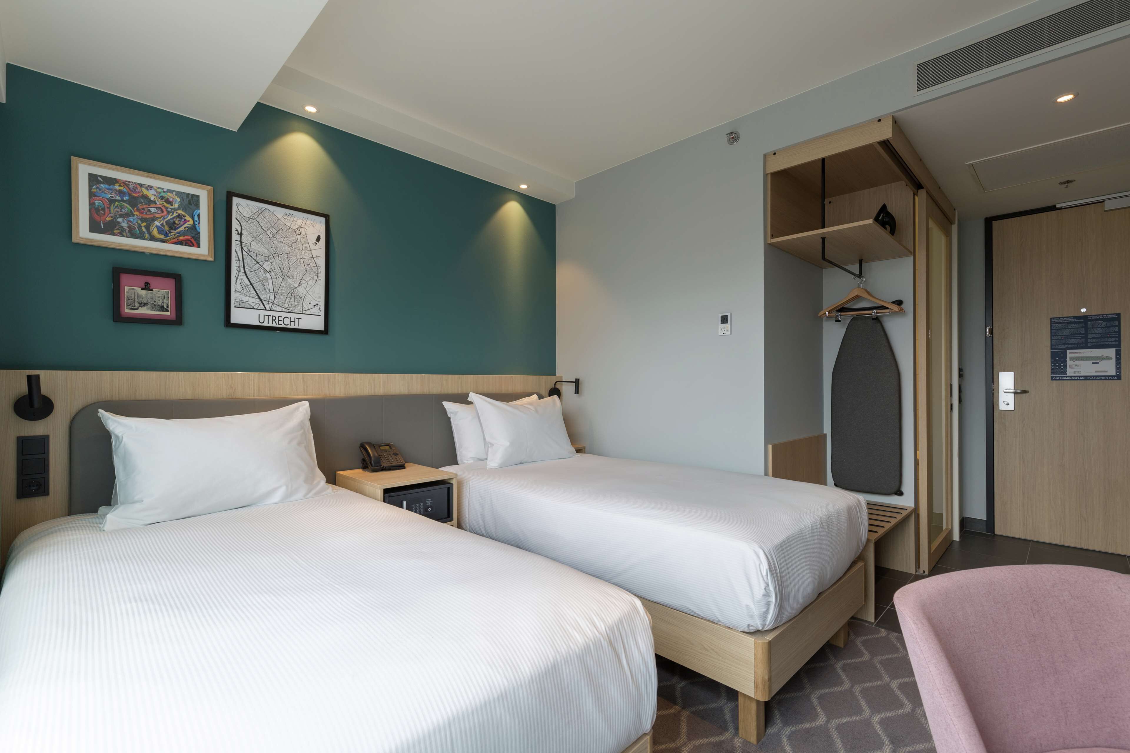 A hotel room with two beds, a desk, and a wardrobe.
