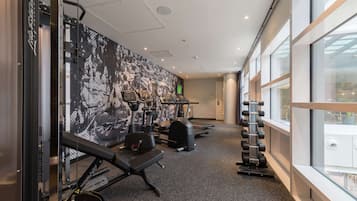 A gym with treadmills, weight machines, and a large window providing natural light.