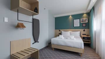 Een moderne hotelkamer met een houten bed, een bankje, een kapstok en een wandplank.