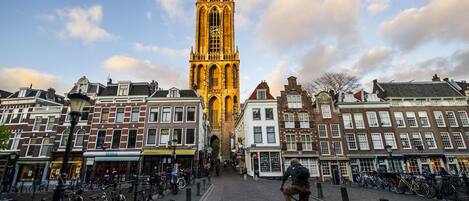 A historic building with a tall tower, surrounded by cobblestone streets and bicycles.