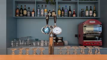 A bar area with a tap, glasses, and shelves of bottles.