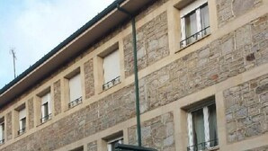 A stone building with multiple windows and signs for a hostel and restaurant. - Valle de San Emiliano (San Emiliano)