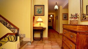 A hallway with a wooden staircase, a lamp, a dresser, and framed pictures on the walls. - Valle de San Emiliano (San Emiliano)