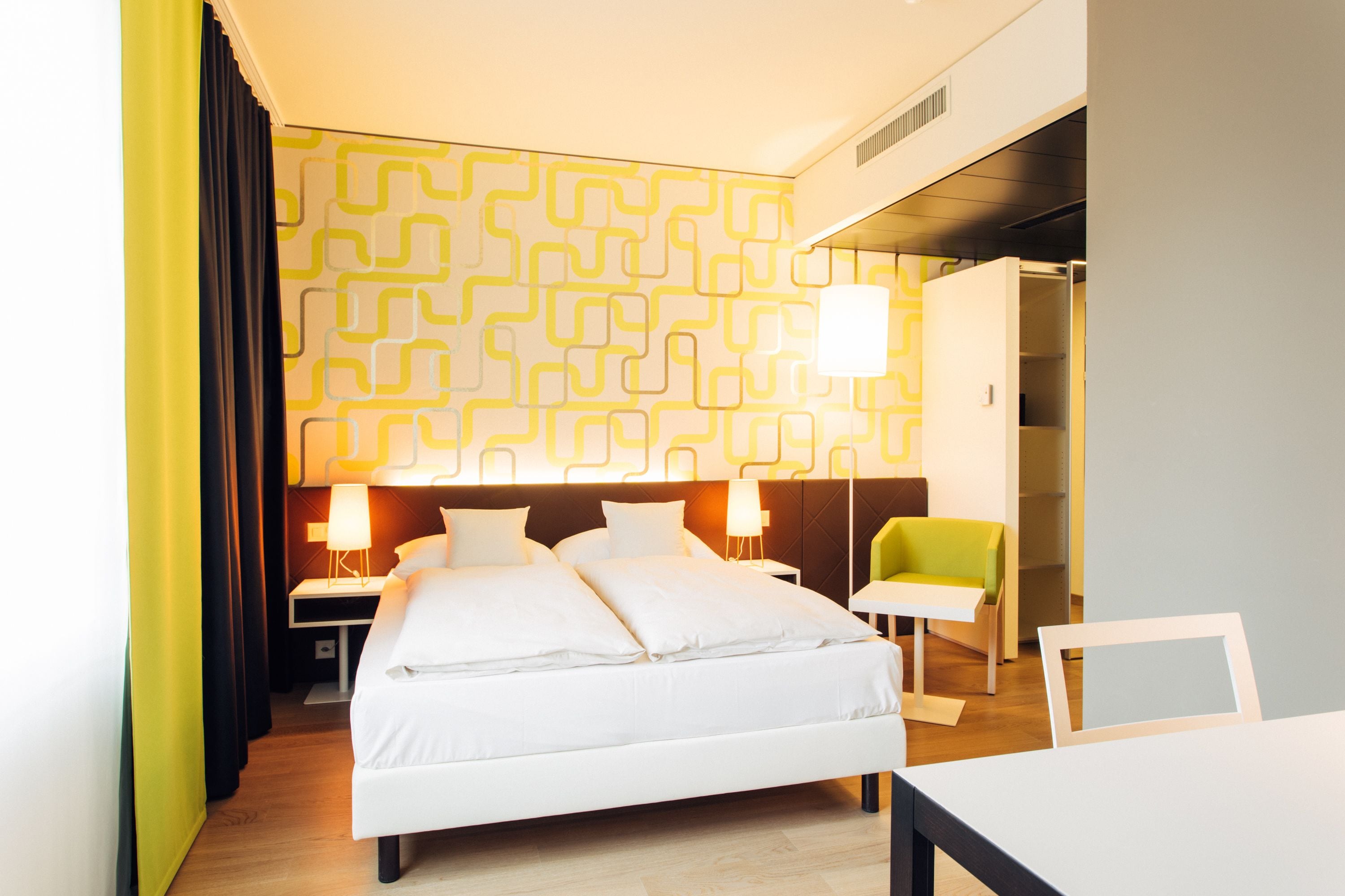 Une chambre d’hôtel comprenant un lit, des tables de chevet, une chaise et une armoire.