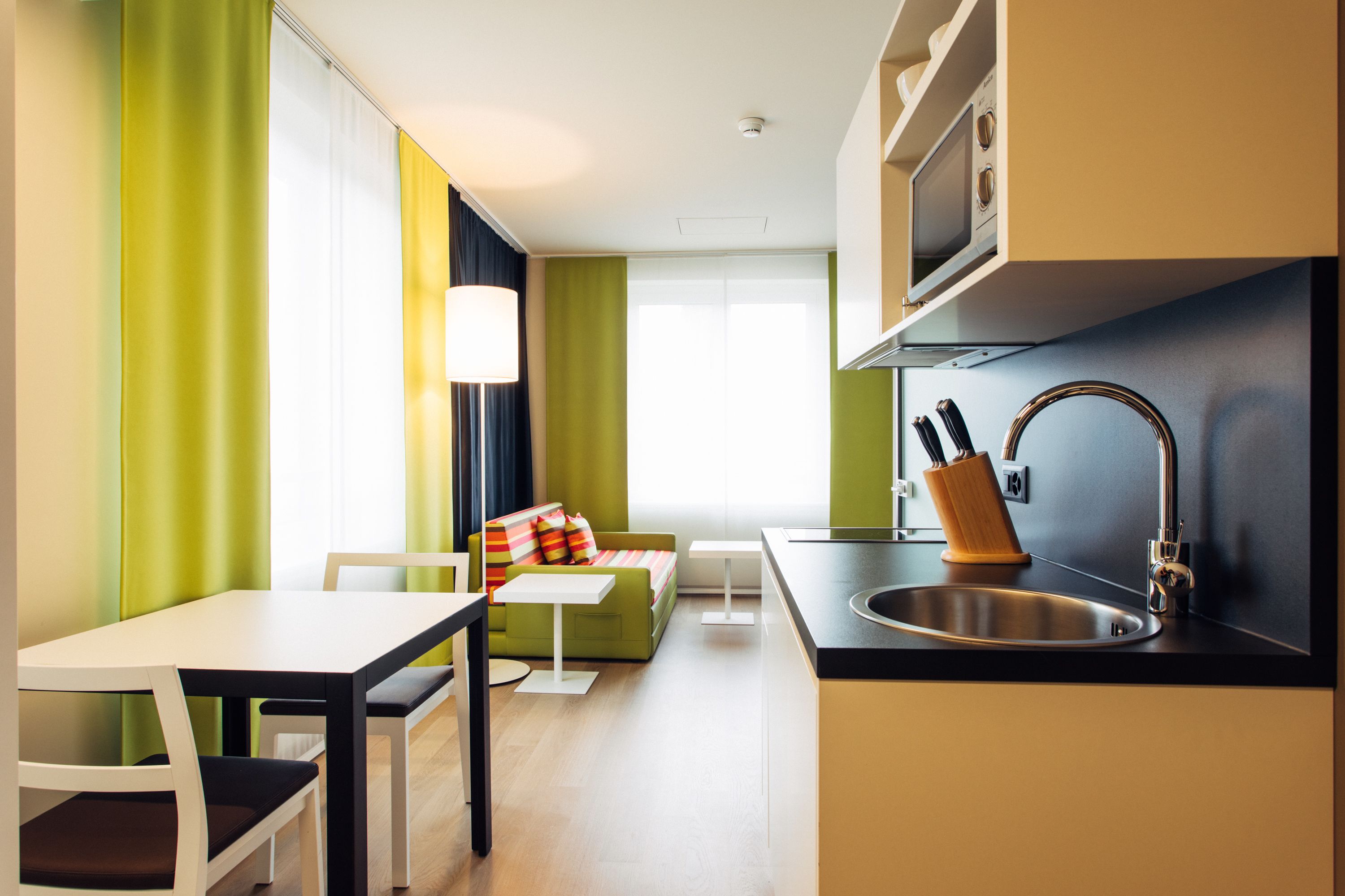 A modern kitchen with a sink, microwave, and a dining area with a table and chairs.