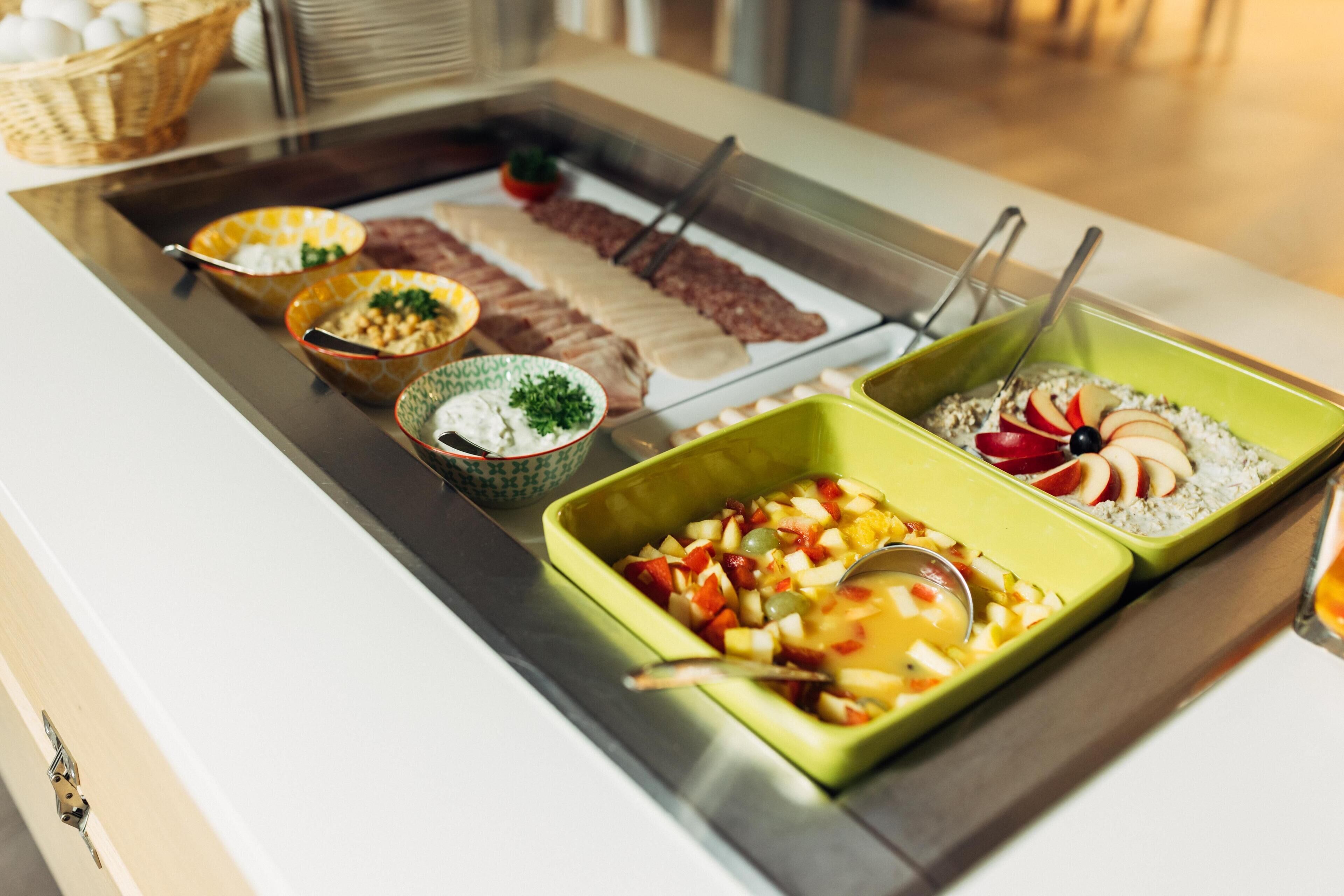 En buffé med ett varierat utbud av mat, inklusive kött, frukt och sallader.