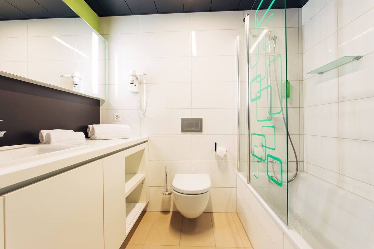 A modern bathroom with a toilet, shower, and sink.