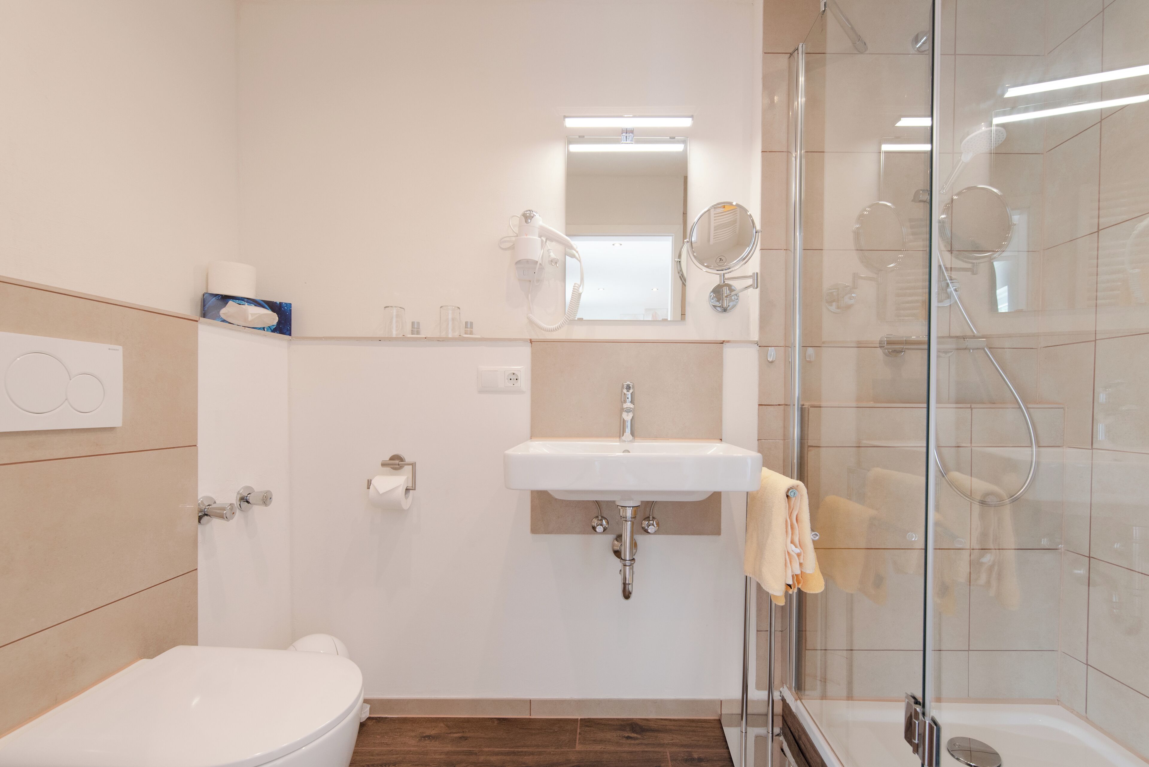 Une salle de bain moderne équipée de toilettes, d’un lavabo et d’une douche à parois de verre.