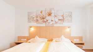Un lit double agrémenté d’une touche de jaune, deux tables de chevet et une œuvre d’art représentant des fleurs, accrochée au mur.