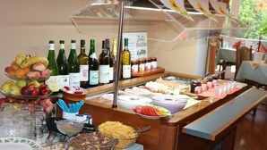 Un buffet proposant une variété de plats, notamment des fruits, des viandes et des desserts, ainsi que plusieurs bouteilles de vin.