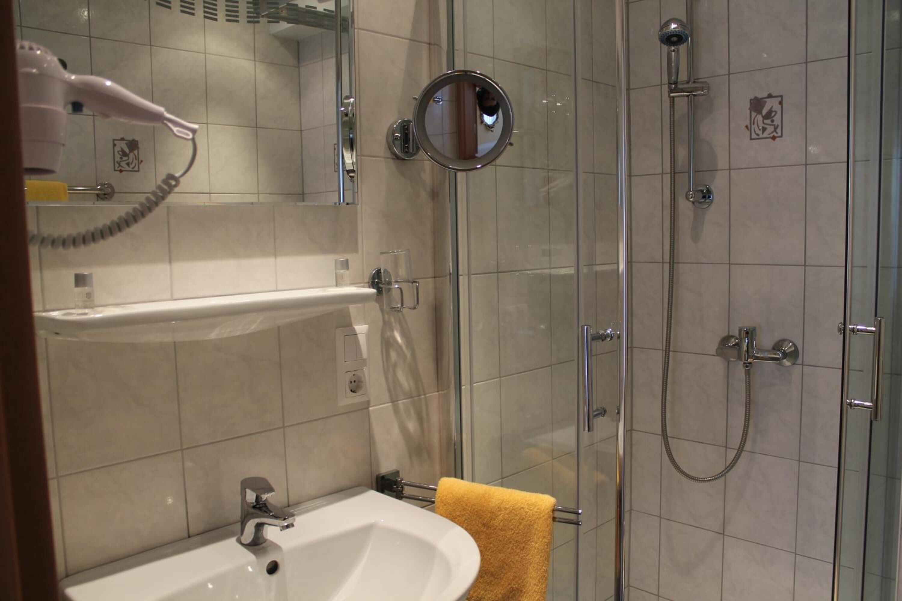 A bathroom with a sink, mirror, and shower.