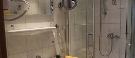 A bathroom with a sink, mirror, and shower.