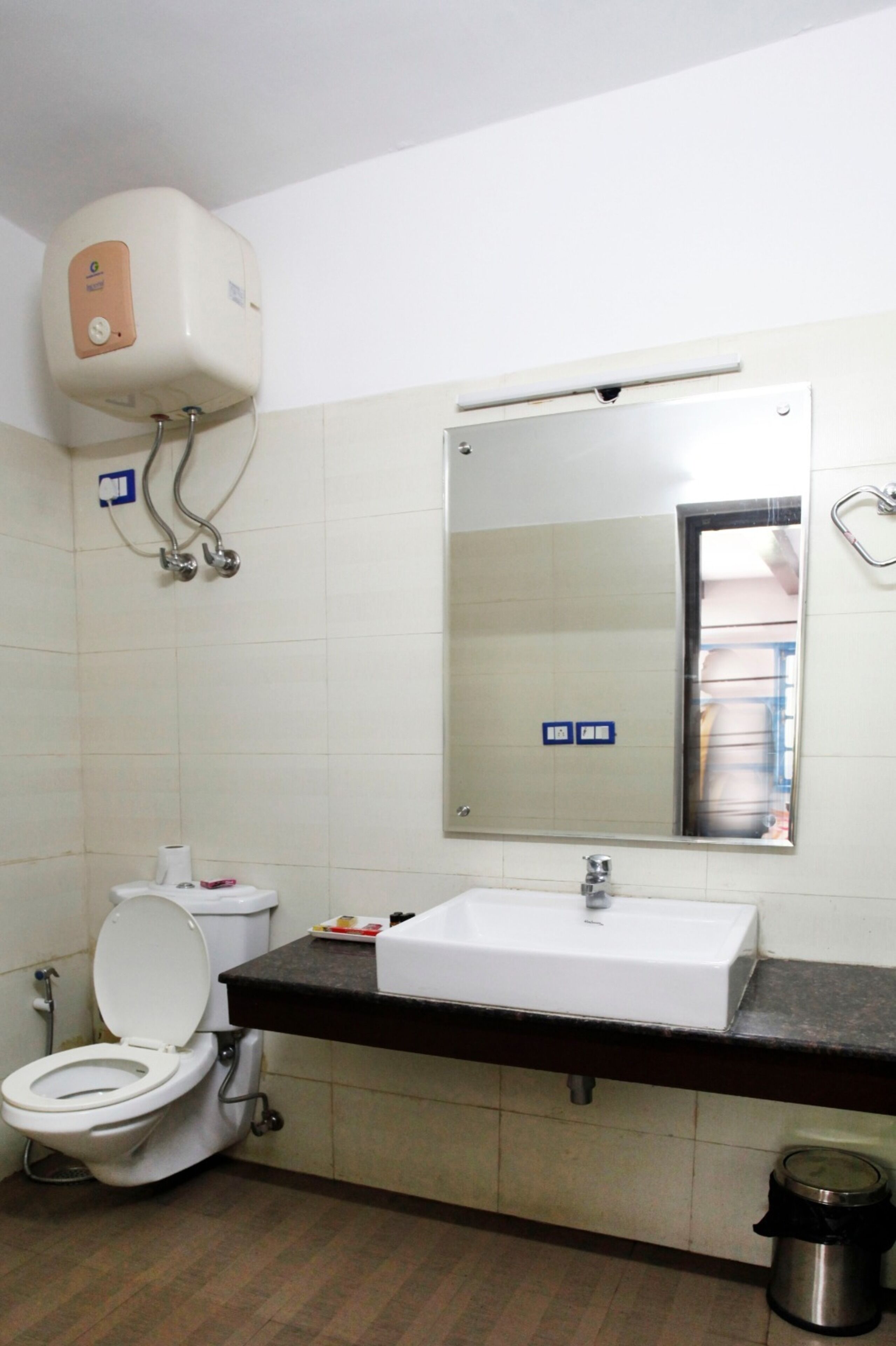 Un baño con inodoro, lavabo, espejo y secamanos.