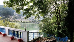 A balcony with a view of a lake and a hillside town. - Manu Maharani Regency (Nainital)