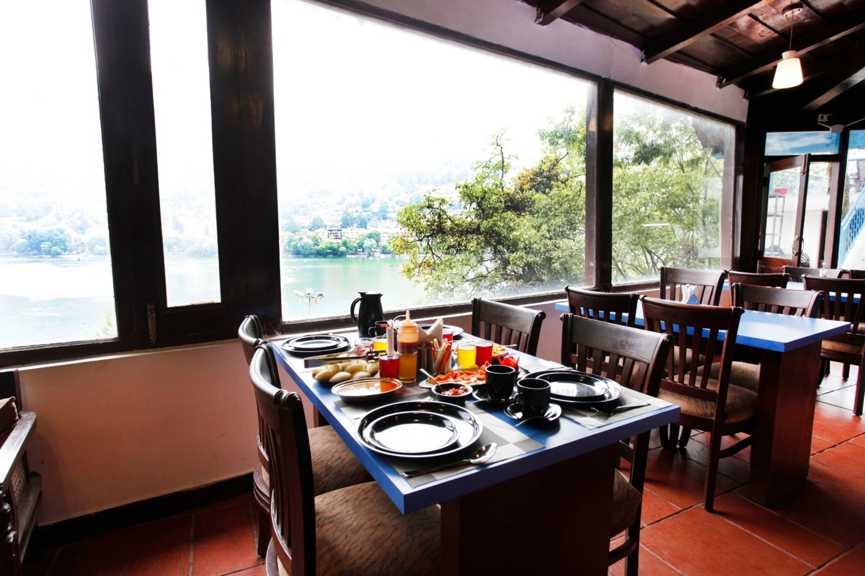 A dining area with a table set for two, overlooking a scenic view of a lake and trees.
