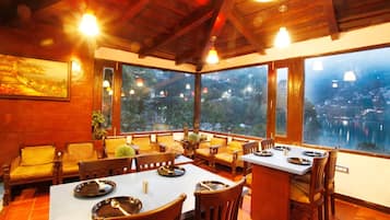 Un comedor con mobiliario de madera y ventanas amplias con vistas a un paisaje urbano.