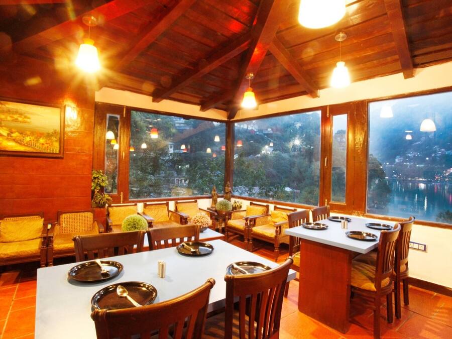 Un comedor con mobiliario de madera y ventanas amplias con vistas a un paisaje urbano.