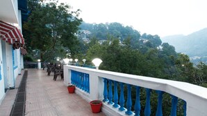 A balcony with a view of a mountainous landscape, potted plants, and a railing with blue accents. - Manu Maharani Regency (Nainital)