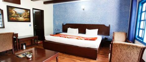 A bedroom with a large bed, wooden furniture, a painting on the wall, and a window with blue curtains.