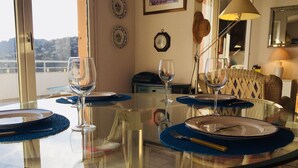 A dining area with a glass table, blue placemats, and wine glasses.