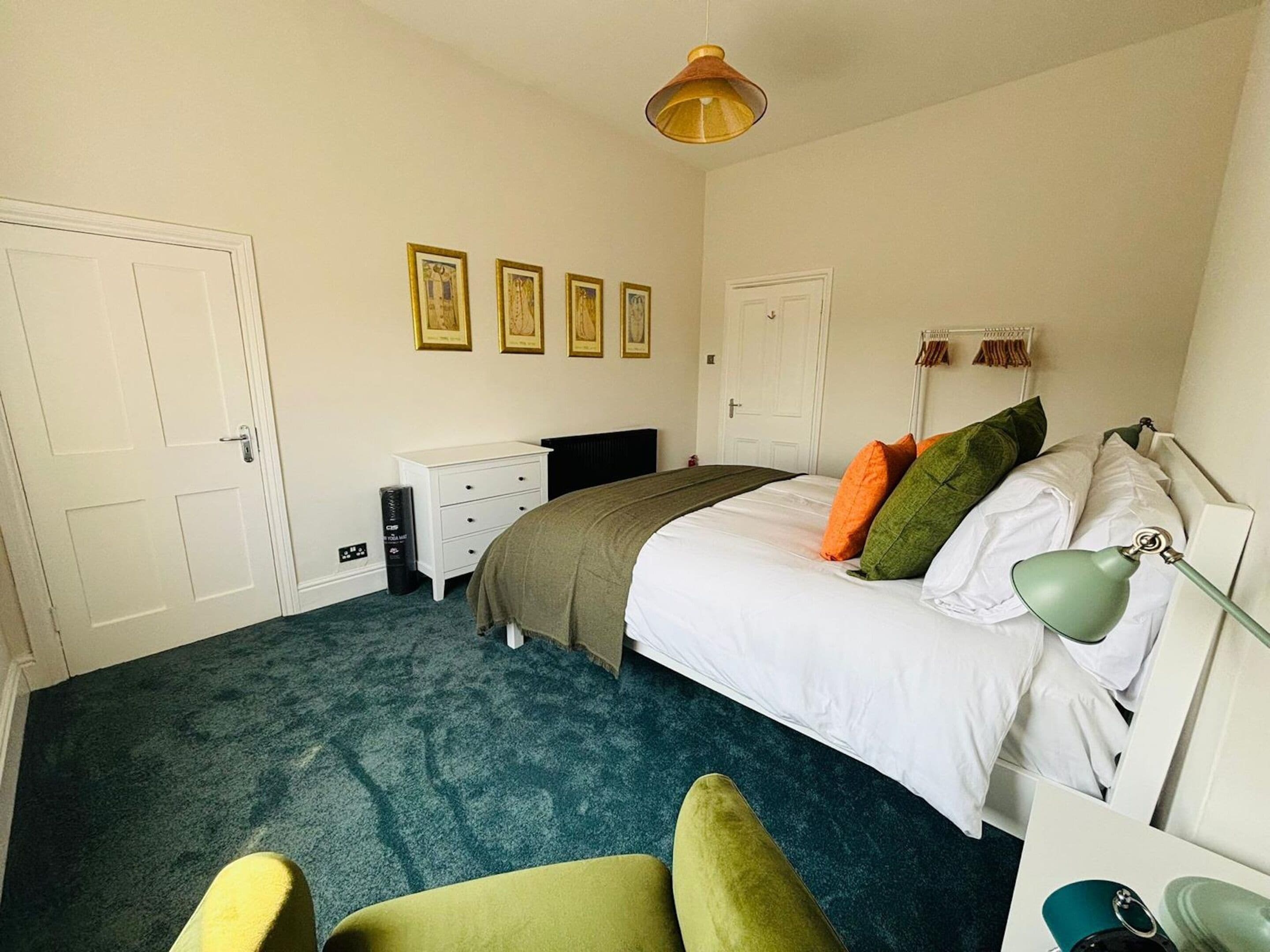 A bedroom with a bed, a desk, a chair, and a lamp.