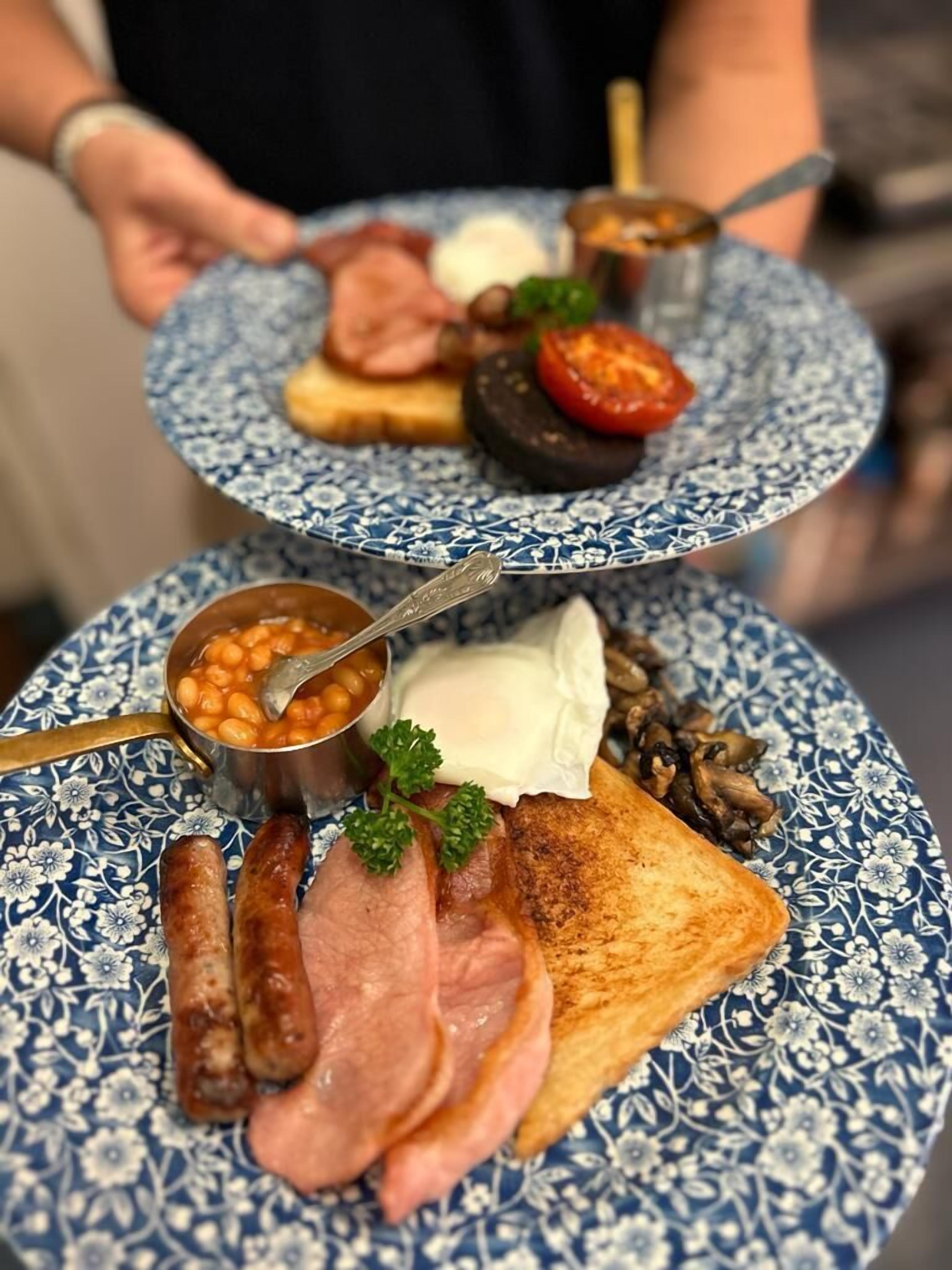 A breakfast tray with toast, sausages, beans, mushrooms, and a slice of cheese.