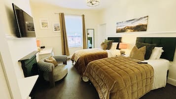 A hotel room with two beds, a television, a window with curtains, and a painting on the wall.