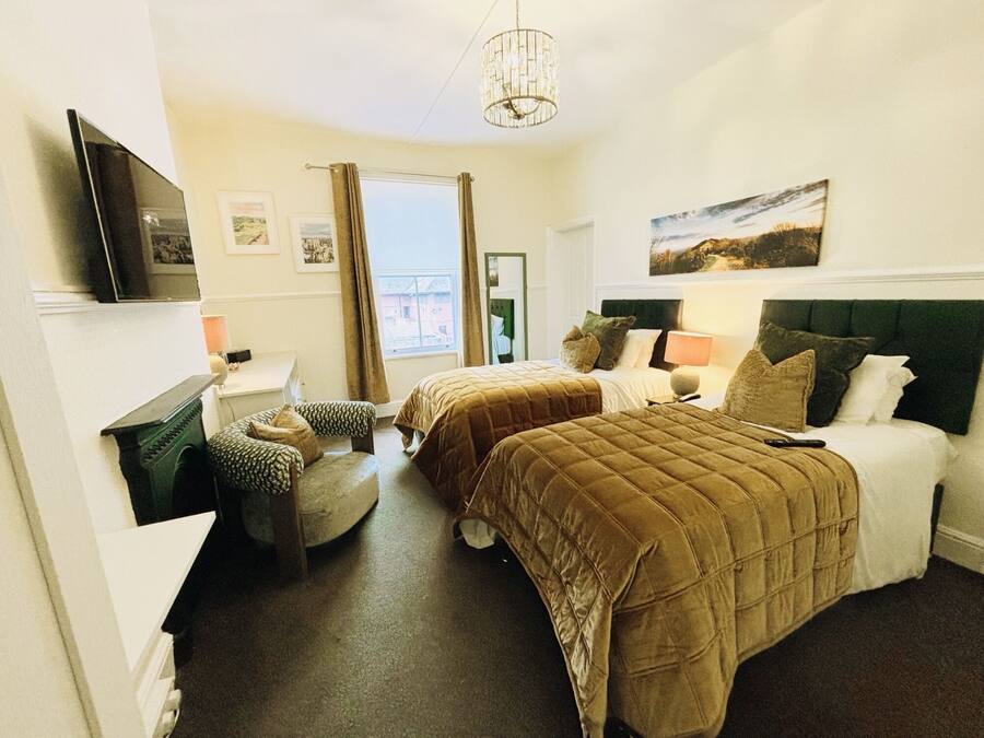A hotel room with two beds, a television, a window with curtains, and a painting on the wall.