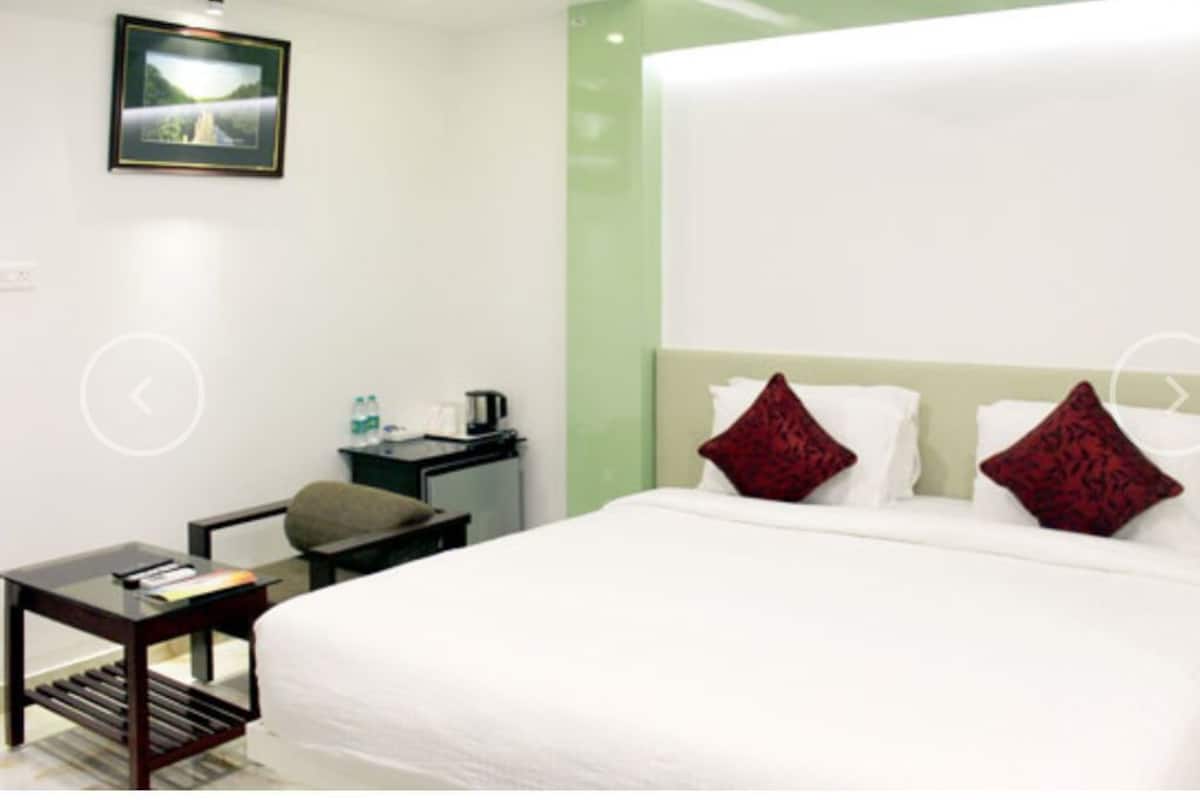 A hotel room with a bed, a desk, a chair, and a small table.