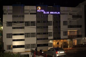 Un hotel de varios pisos con un letrero llamativo que dice "HOTEL BLUE MMARLIN".